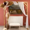 Arche en bois bohème décorée pour mariage Arche en bois décorée avec voilage blanc, fleurs blanches et bordeaux, pampas et banc capitonné, installée dans un décor bohème pour événement.