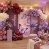 Décor anniversaire 50 ans pour Marjorie avec panneaux mauves, ballons roses, blancs, violets et bordeaux, papillons, grande libellule décorative et table décorée.
