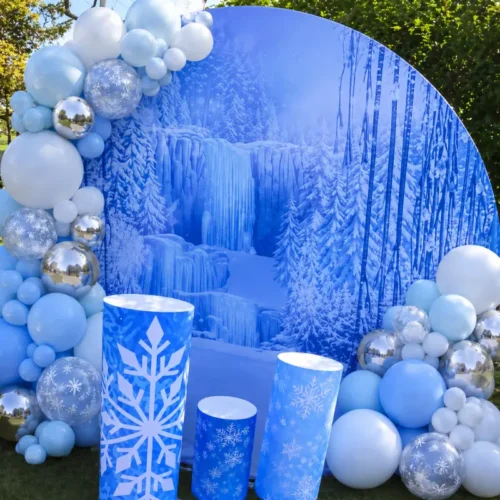 Décor événementiel thème hiver avec grand fond rond bleu représentant une forêt glacée, colonnes à flocons de neige et ballons bleu ciel, blanc et argent.
