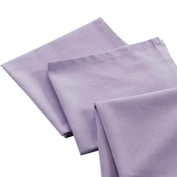 Serviette de table lilas pliées et disposées sur fond clair.