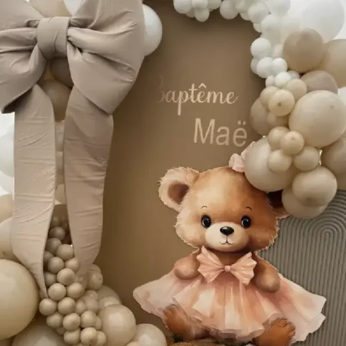 Ourson décoratif en PVC avec robe rose, utilisé dans une décoration de fête avec arche de ballons beige et nœud géant.