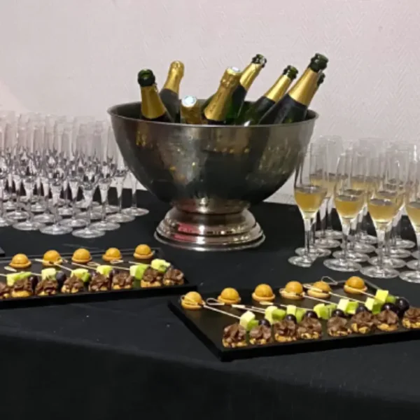 Vasque inox à champagne en location pour vos événements Vasque à champagne en inox avec bouteilles et flûtes sur un buffet traiteur décoré.