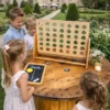 Enfants jouant au jeu Puissance 4 en bois dans le jardin d’un château lors d’un événement ou d’un mariage.