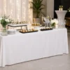 table pliante rectangulaire napée Table pliante rectangulaire recouverte d’une nappe blanche, décorée avec des fleurs, des assiettes, des verrines et des verres dans une ambiance de réception élégante.