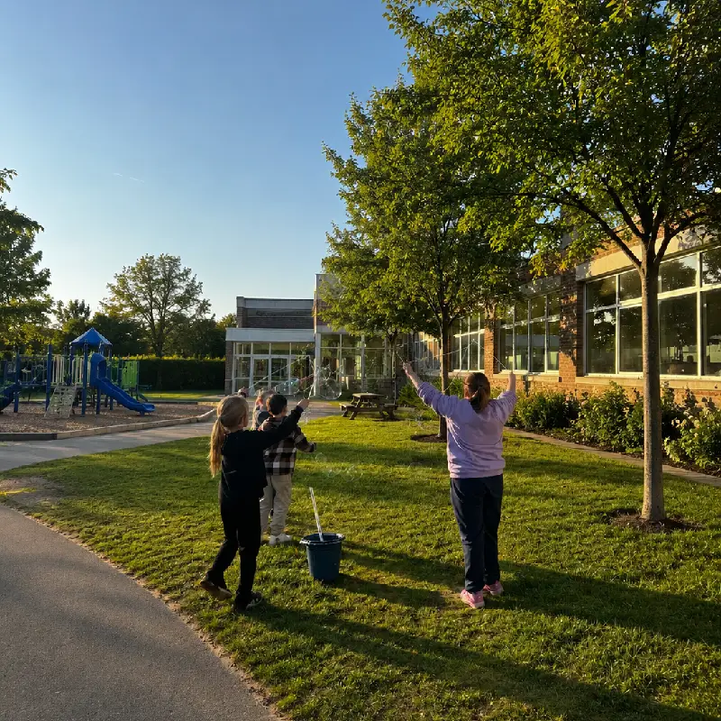 Enfants réalisant des bulles de savon géantes dans le jardin d’une école.