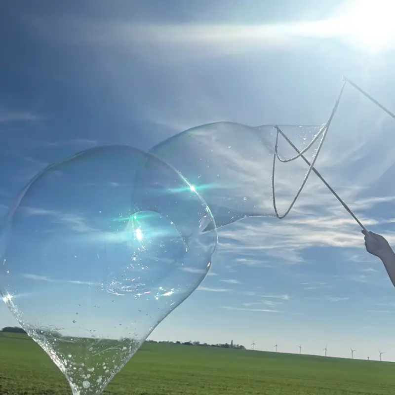 Grande bulle de savon créée avec une baguette lors d’une animation enfants en extérieur.