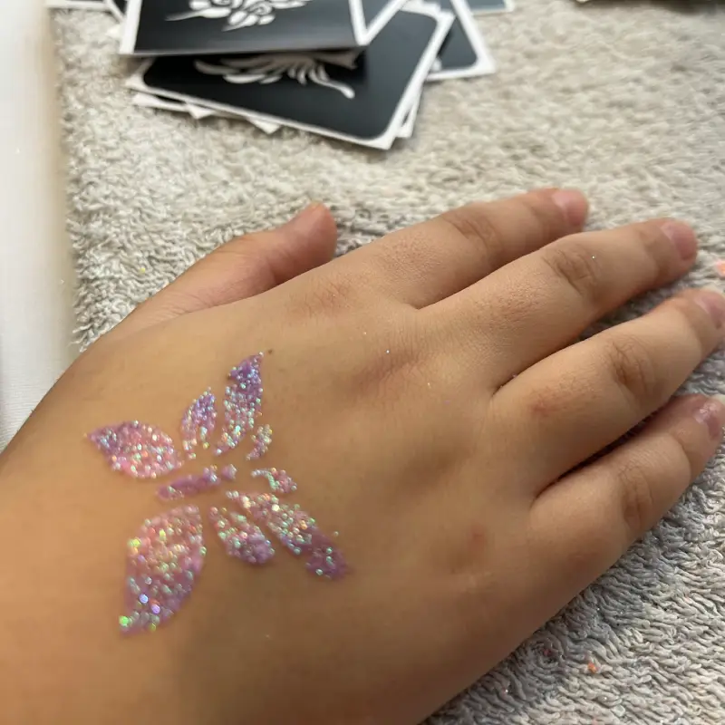 Tatouage pailleté papillon sur la main d’un enfant.