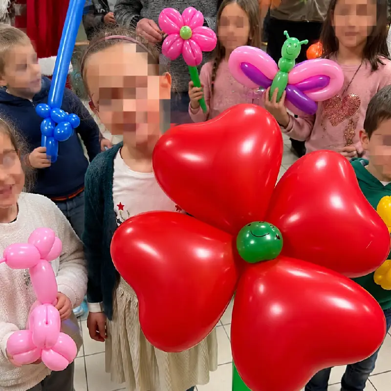 Enfants tenant des sculptures de ballons lors d’une animation de kermesse d’école.